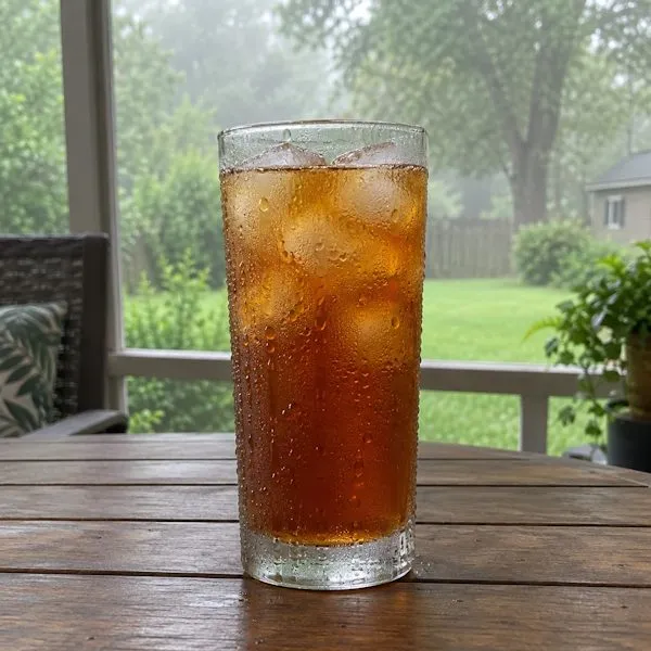 Glass of iced tea covered in condensation on a porch table on a humid day